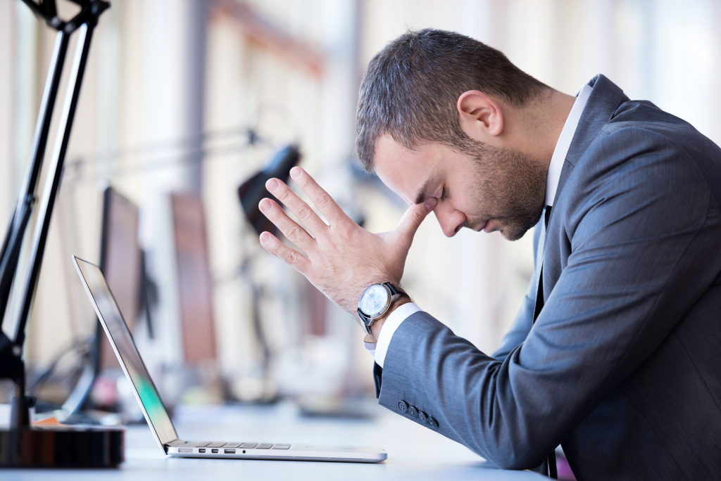 Young businessman stressed out sitting at work computer table